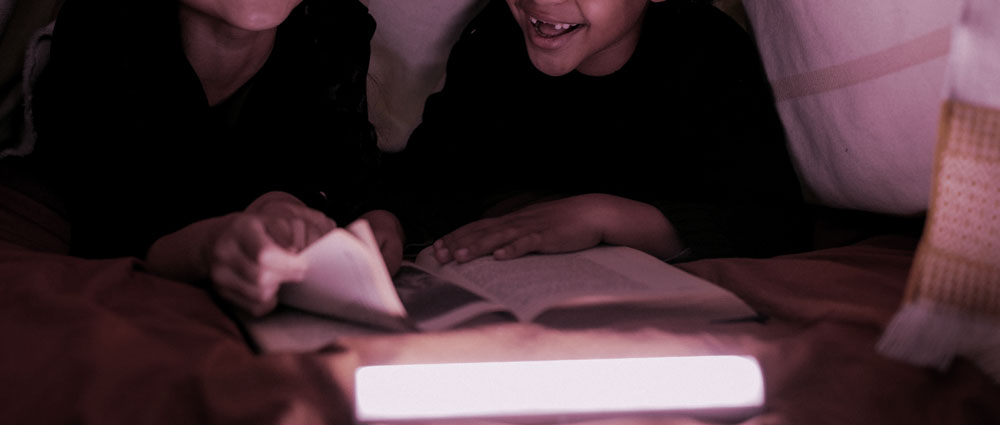 Niños leyendo en la cama historias de terror, recomendaciones de cuentos y libros para Halloween