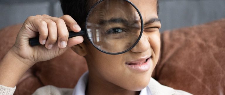 Niño con lupa para ilustrar las recomendaciones de series libros infantiles de investigación.