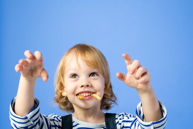 Cuentos para lavarse los dientes representados por un niños con cepillo de dientes y espuma en la boca, muy sonriente.