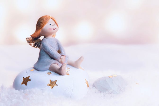 Muñeca sentada sobre la nieve para representar cuentos infantiles sobre el invierno
